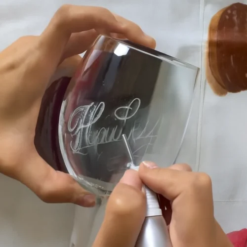 Close-up of laser glass engraving process creating custom designs.